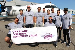 Team posing in front of plane