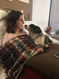 Woman living with ALS laying in bed with dog