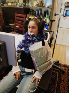 Zehra sitting in her wheelchair, using eye gaze technology